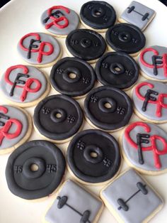 decorated cookies with black and red frosting on a white plate in the shape of buttons