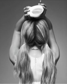 a woman with long hair holding a bowl on her head