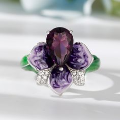 Flowers are one of the most common motifs used in art and design, and this is particularly true with jewelry. Featuring a multi-petal design, this flower ring represents the unmatched beauty of nature. Crafted in fine sterling silver, this ring is topped with a detailed flower, its petal shimmering with purple enamel, sparkling pear, and round stones. The shank is designed with green enamel leaves. Buffed to a brilliant shine, this beguiling blossom is certain to never fade away.Carat Weight: 4. Jeulia Jewelry, Top List, Amethyst Purple, Green Enamel, Blooming Flowers, Flower Ring, Cocktail Rings, Quality Jewelry, Diamond White