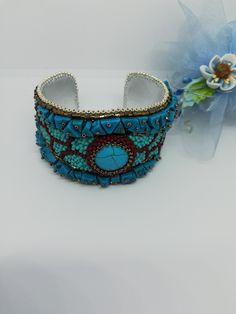 Beautiful and elegant bracelet in a slightly ethnic style, hand embroidered with a central turquoise cabochon and aulite gems. It is difficult and slow work, it took many hours of work from planning to realization of the final project. Each bead is individually hand sewn to create the final design. Inside the bracelet is covered in natural leather which gives a soft touch to the skin. This bracelet is comfortable to wear, goes perfectly with clothes of different colors. The colors used recall summer, the sea and the sun... The width of the bracelet is 4cm (1.6 inches). It has a brass plate inside that holds its shape and fits any wrist size. Wearing this bracelet will make you feel unique and special. Each piece is unique. If you would like a personalized bracelet in the colors of your cho Bohemian Turquoise Beaded Bracelets For Festivals, Handmade Turquoise Beaded Bracelets For Festivals, Handmade Turquoise Bracelet For Festivals, Turquoise Beaded Bracelets As Festival Gifts, Turquoise Beaded Cuff Bracelet Bangle, Multicolor Embroidered Bangle Jewelry, Artisan Turquoise Beaded Bangle Bracelets, Artisan Turquoise Beaded Bangle Bracelet, Bohemian Adjustable Jeweled Bracelet