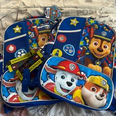 three children's backpacks with paw patrol characters on them sitting on a bed