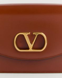 Valentino Garavani Vain shoulder bag in shiny calfskin with metallic VLogo Signature detail. The bag can be carried on the shoulder/cross body thanks to the sliding chain. - Antique gold-finish hardware - Magnetic closure with antique brass-finish VLogo - Nappa lining. Interior: two compartments, zip pocket and slip pocket Shoulder strap drop length: min. 27 cm - 52 cm max. / min. 10.6 cm to max. 20.4 in. - Dimensions: W24xH16xD8 cm / W9.4xH6.2xD0.7 in. - Made in Italy Luxury Tan Crossbody Shoulder Bag, Elegant Gold Shoulder Bag With Logo, Luxury Shoulder Bag With Metal Logo, Formal Brown Shoulder Bag With Gold-tone Logo Plaque, Elegant Logo Crossbody Shoulder Bag, Formal Logo Satchel Shoulder Bag, Luxury Shoulder Bag With Logo, Modern Gold Shoulder Bag With Logo, Classic Gold Shoulder Bag With Logo