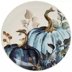 a decorative plate with blue pumpkins and leaves painted on the front, side view