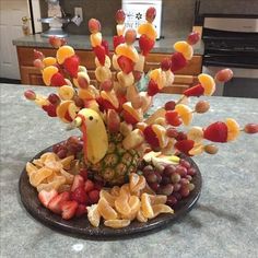 a fruit platter with bananas, strawberries, grapes and pineapples in the shape of a bird