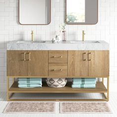 a bathroom vanity with two mirrors above it and towels on the counter top next to it