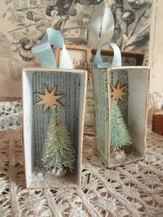 two small wooden boxes with christmas trees in them sitting on a lace doily tablecloth