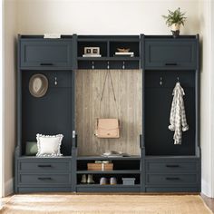 an entryway is decorated in black and white with gray drawers, coat rack, and bench