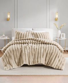 a bed with a white comforter and pillows on top of it in a room