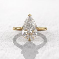 a pear - shaped diamond ring on a white surface