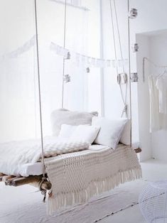 a white bedroom with a swing bed and pillows