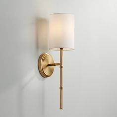 a wall light with a white shade on it's side and a lamp attached to the wall