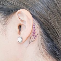 a woman's ear has a small flower tattoo on it