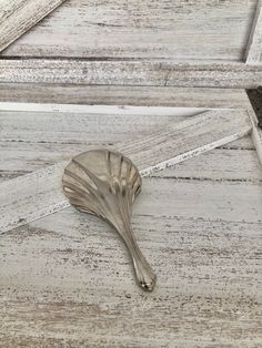 a silver spoon sitting on top of a white wooden floor next to a window sill