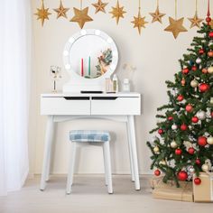 a white desk with a mirror and christmas decorations on it next to a small tree