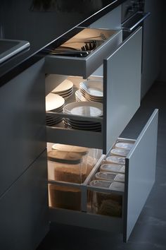 an open drawer in a kitchen filled with plates and bowls