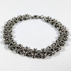 A chainmaille bracelet using the "Celtic Visions" weave. I use tiny pliers to open each individual ring, weave it into the chain and then close it, carefully lining up the ends so they're flush. * Won't tarnish or change color over time * Can be cleaned with warm soapy water * Made with 20 gauge stainless steel jump rings and a 9mm stainless steel clasp * Bracelet length includes the length of the clasp. If you don't know your bracelet size, measure around your wrist and then add 1/4" to 1", depending on how tight you'd like your bracelet to fit. A flexible measuring tape is a great way to measure if you have one - if not, you can use string or a strip of paper to measure your wrist and then hold it up to ruler to find the length. Adjustable Chainmail Chain Bracelet As A Gift, Metal Chain Link Bracelet For Jewelry Making, Metal Box Chain Bracelet, Silver Chainmail Bracelet As A Gift, Silver Chainmail Chain Bracelet As Gift, Metal Chainmail Bracelet, Adjustable Chainmail Chain Bracelet, Stainless Steel Jewelry Making Jump Rings, Hypoallergenic Metal Bracelets For Jewelry Making