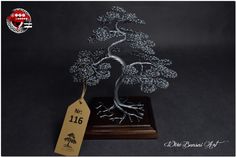 a metal bonsai tree on a wooden stand with a price tag hanging from it