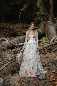 a woman in a long white dress standing on rocks