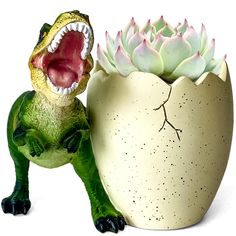 a ceramic dinosaur with its mouth open next to a potted succulent plant