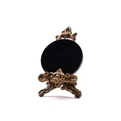 a black and gold brooch sitting on top of a white table next to a mirror