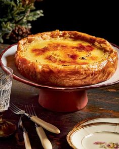 a quiche sitting on top of a red plate next to silverware and forks