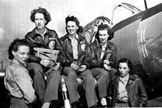 four women sitting on the wing of an airplane