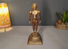 a gold colored statue sitting on top of a table next to a lamp and potted plant