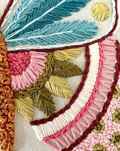 a close up of a piece of cloth with different colored feathers on it and some crochet