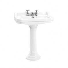 a white pedestal sink with two faucets on it