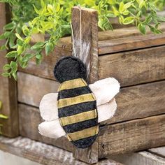 a stuffed bee hanging from a wooden planter