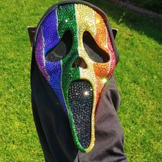 a person wearing a colorful mask on top of their head with grass in the background