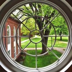 a circular window in the middle of a building with trees and grass on both sides