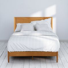 a bed with two pillows on top of it in a room that has white walls