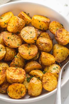 a white bowl filled with cooked potatoes and garnished with parsley