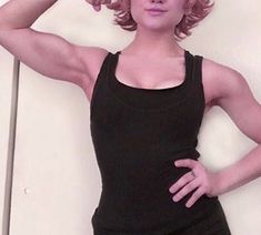 a woman with pink hair is posing for the camera while holding her hands on her head