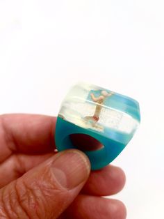 A child playing with the sea in a diorama scene.  This ring is made with a miniature, white and blue resin bedded in a special mold and after polished to be shinny. The ring is a starting conversation!  I can enlarge to a 7 USA size. If you need help for your ring size, check out http://en.wikipedia.org/wiki/Ring_size  My work features brilliant colors and clear resin.The resin results in a durable piece that has a natural shine and is resistant to scratches. I hand sand the edges for a smooth piece with a beautiful luster. I hand make each piece in my studio in Barcelona and no two are alike. This jewelry is handmade and slight imperfections are part of the character of the piece.  I will send the order packed in a recycled craft box, ready to gift! I ship through registered mail with the Ocean-inspired Blue Ring For Gifts, Ocean-inspired Blue Ring For Gift, Ocean-inspired Blue Rings As Gifts, Unique Blue Resin Rings, Handmade Blue Resin Rings, Blue Resin Rings For Gifts, Blue Resin Rings Perfect As Gifts, Blue Resin Rings Perfect For Gifts, Ocean-inspired Blue Resin Jewelry