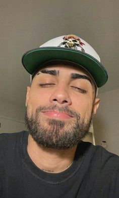 a man with his eyes closed wearing a hat and looking up at the ceiling in front of him