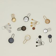 several different types of metal objects on a white surface, including pins and spoons