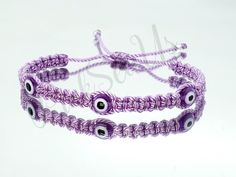 two purple bracelets with evil eyes on them