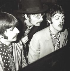 three men in suits and ties are looking at something on the computer screen while another man is wearing a top hat