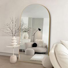 a mirror sitting on top of a wooden floor next to a white couch and table