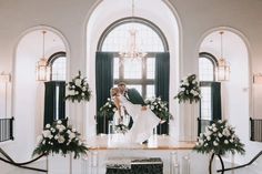 a bride and groom kissing in front of an arch decorated with white flowers at their wedding