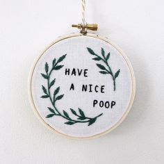 a hand embroidered hoop hanging on a wall with the words have a nice poop