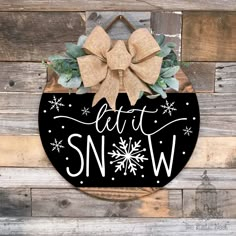 a black and white sign that says let it snow on the side of a wooden wall