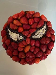 a cake made to look like a face with strawberries and chocolate chips on it