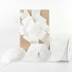 two rolls of toilet paper next to a gift wrapped in white lace with a bow