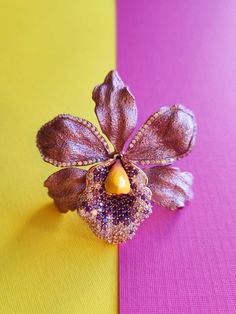 a flower brooch sitting on top of a purple and yellow table