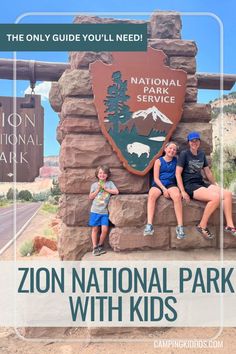 two people sitting on a sign at the entrance to national park with kids in front