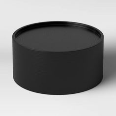 an empty black plastic container on a white surface with no one around it or the lid