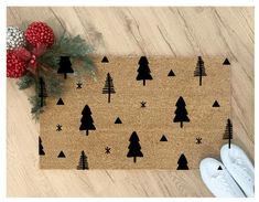 a door mat with christmas trees on it next to a pair of white shoes and a red poinsetti